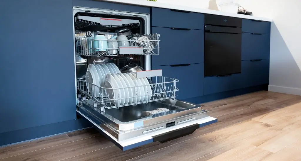 Lave-vaisselle encastré ouvert et rempli de vaisselle propre dans une cuisine bleue moderne - réparation lave-vaisselle Genève, Suisse Dépannage