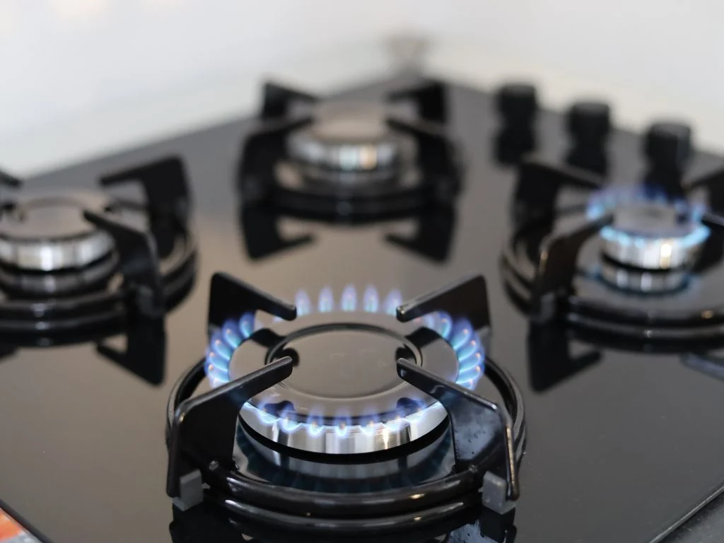 Flamme bleue d'un brûleur allumé sur une plaque de cuisson à gaz noire - réparation plaque de cuisson Genève, Suisse Dépannage