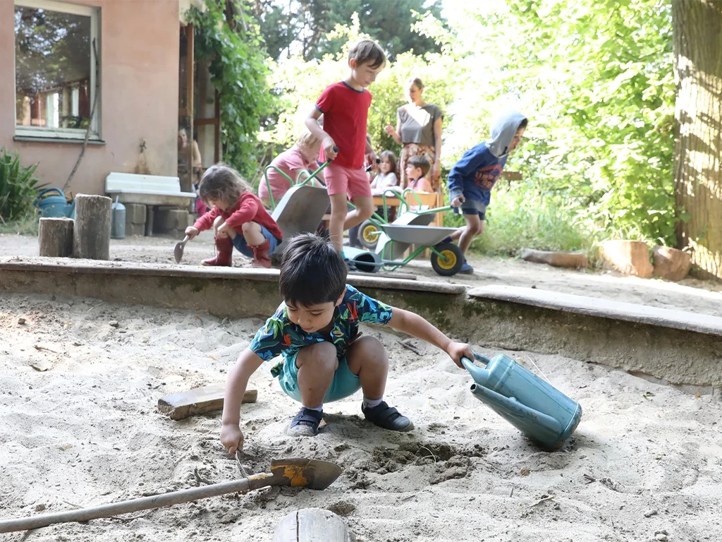 Enfants jouant dans un bac à sable dans le jardin d'une crèche - Suisse Dépannage, partenaire technique des crèches à Genève