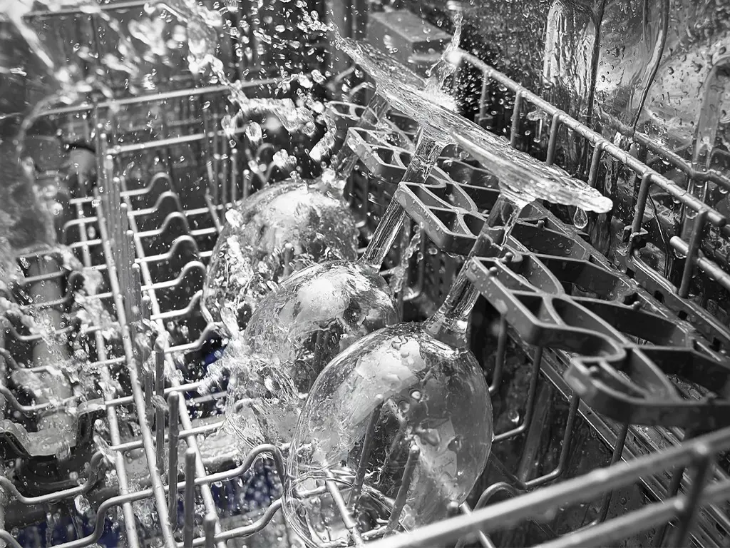 Verres à pied éclaboussés d'eau à l'intérieur d'un lave-vaisselle en fonctionnement - réparation lave-vaisselle Genève, Suisse Dépannage