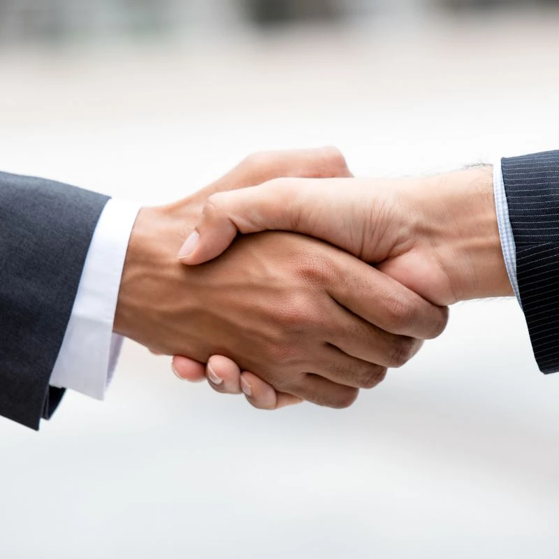Poignée de main entre deux professionnels en costume - Suisse Dépannage, partenaire technique des régies et professionnels à Genève