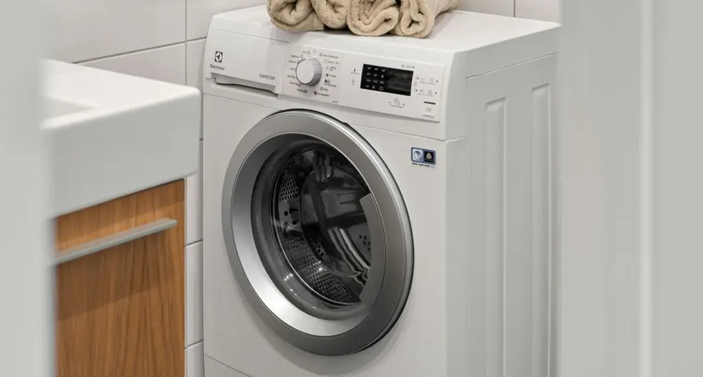 Lave-linge Electrolux blanc dans une salle de bain avec serviettes pliées sur le dessus - réparation lave-linge Genève, Suisse Dépannage