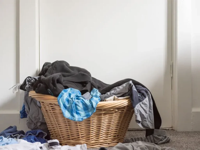 Panier en osier débordant de linge sale entassé dans une entrée - réparation lave-linge Genève, Suisse Dépannage